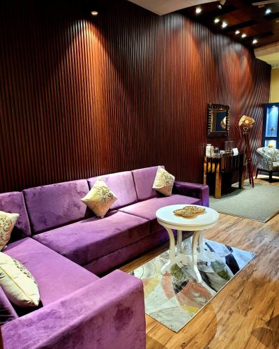 a purple couch in a living room with a table at Victorian Elegance Luxury Stays in Amritsar