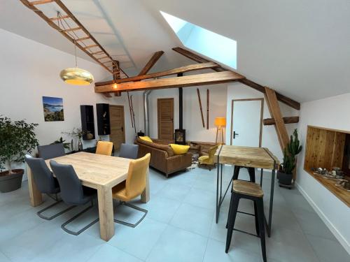 a dining room and living room with a wooden table and chairs at Le Couleau in Chateauroux-les-Alpes