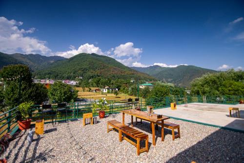 a park with benches and a view of mountains at The Jungalow by AVVAs Stays in Bīr