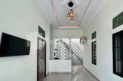a hallway with white walls and a ceiling with a tv at Trubus Guesthouse Syariah Magelang mitra RedDoorz in Sumberrejo