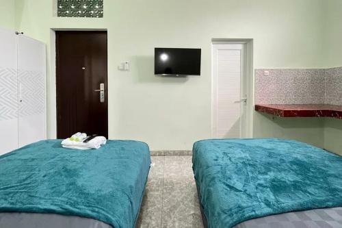 a bedroom with two beds and a flat screen tv at Trubus Guesthouse Syariah Magelang mitra RedDoorz in Sumberrejo