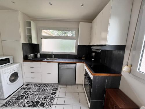 Elle comprend une petite cuisine avec des placards blancs et une fenêtre. dans l'établissement Charmant duplex T3 proche de Paris & Versailles, à Bois-dʼArcy