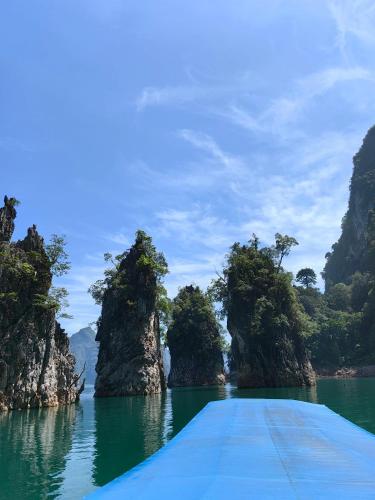 a boat in a body of water with limestone formations at Khao Sok Country Resort in Khao Sok