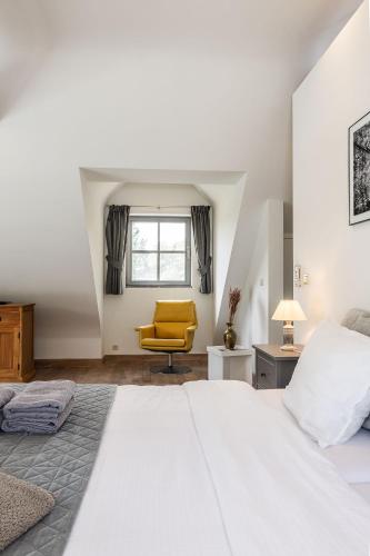 a bedroom with a white bed and a yellow chair at Domein Den Buiten Bed And Breakfast DnD in Sint-Niklaas