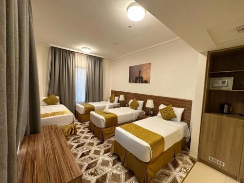 a hotel room with three beds in a room at Sama Al Amany Hotel in Makkah