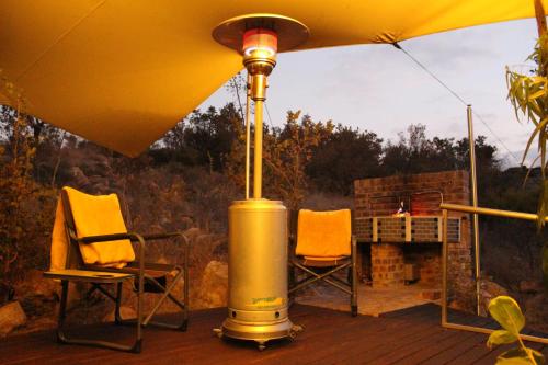 a yellow heater sitting on a deck with two chairs at Luxury Treehouse on Bronberg Ridge in Tierpoort