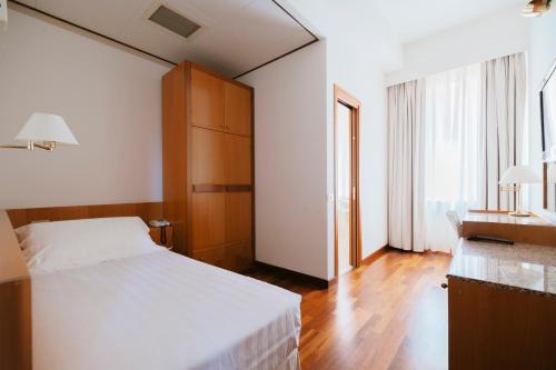 a bedroom with a white bed and a wooden cabinet at Hotel Miramare in Civitanova Marche