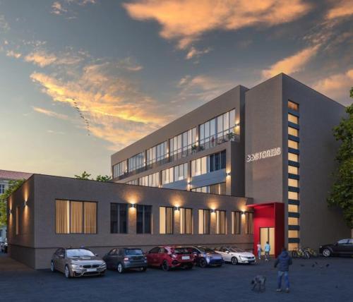 a building with cars parked in a parking lot at Studio on Laisves Aleja, Central Kaunas - Self Check In in Kaunas