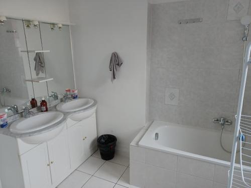 La salle de bains blanche est pourvue de 2 lavabos et d'une baignoire. dans l'établissement F3 ensoleillé très calme, à Maisons-Alfort