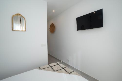 a living room with white walls and a flat screen tv at La morada de Rosafina in Frigiliana