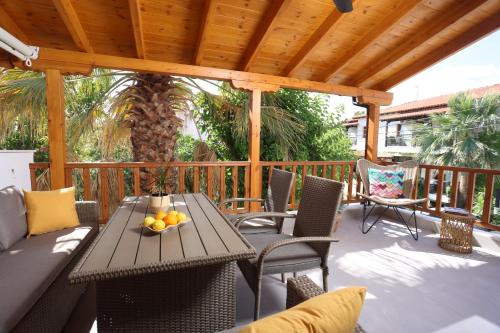 eine Terrasse mit Tisch und Stühlen auf einem Deck in der Unterkunft Blue Sand Apartment in Pefkohori