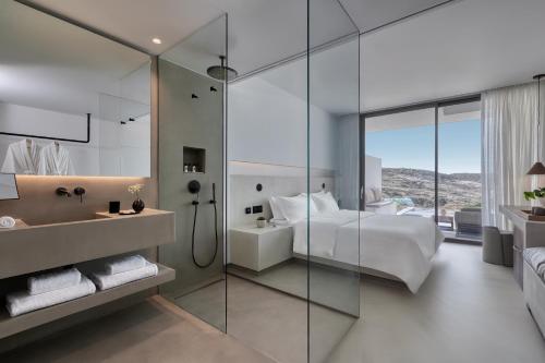 a bathroom with a shower and a bed and a sink at Domes White Coast Milos, Adults Only - Small Luxury Hotels of the World in Mytakas