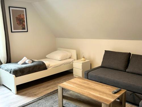 une petite chambre avec un lit et un canapé dans l'établissement Stay Nest Komfort Ferien- und Monteurwohnungen Küche-Garten, à Liesborn