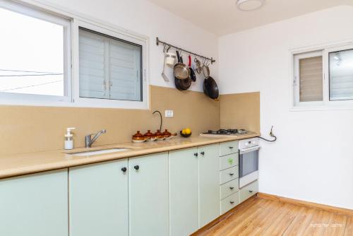 a kitchen with white cabinets and a sink at דירה קסומה עם נוף לים in HaBonim