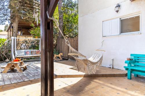 a porch with a hammock and a blue bench at דירה קסומה עם נוף לים in HaBonim
