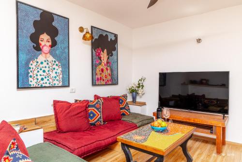 a living room with a red couch and a table at דירה קסומה עם נוף לים in HaBonim
