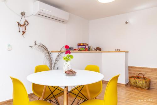 a dining room with a white table and yellow chairs at דירה קסומה עם נוף לים in HaBonim