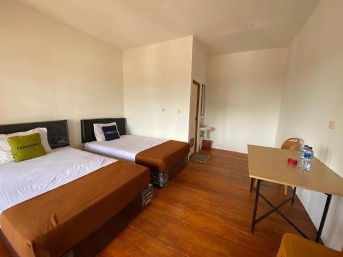 a small room with two beds and a table at Urbanview Hotel D'Pineapple Villa Ciater by RedDoorz in Subang