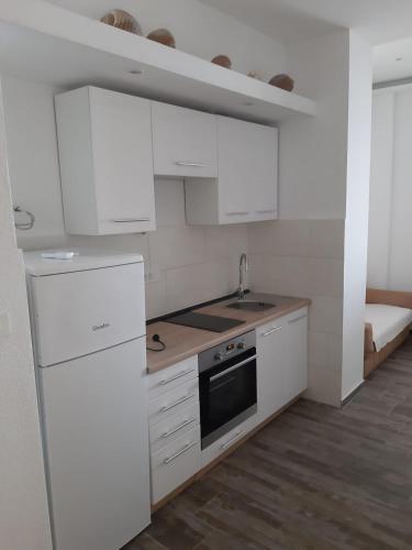 a kitchen with white cabinets and a sink and a stove at Apartmani Marija Mljet in Sobra