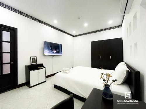 a bedroom with a bed and a table and a tv at 5H Garden in Ho Chi Minh City