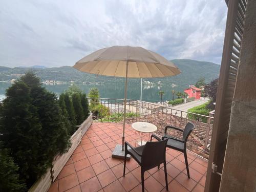 a patio with a table and two chairs and an umbrella at Arbostora Charme Hotel in Morcote