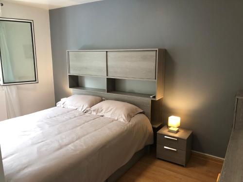 - une chambre avec un grand lit blanc et une tête de lit dans l'établissement La Sapiniere, à Annecy