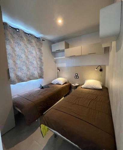 une chambre avec deux lits et une fenêtre dans l'établissement Mobil home climatisé très récent tout confort 6 personnes, à Vendays-Montalivet