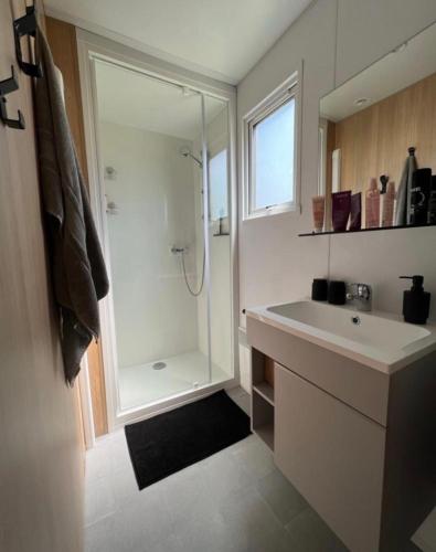 une salle de bain blanche avec une douche et un lavabo dans l'établissement Mobil home climatisé très récent tout confort 6 personnes, à Vendays-Montalivet