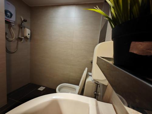 a bathroom with a toilet and a potted plant at Cosy Designer's Home By The Mountain in Lumut