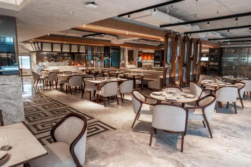 a restaurant with tables and chairs in a room at Mövenpick Hotel Jakarta City Centre in Jakarta