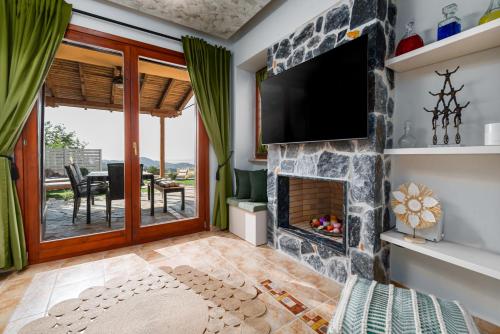 a living room with a stone fireplace and a flat screen tv at Lous House in Agia Paraskevi
