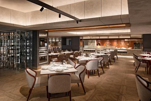 a restaurant with tables and chairs and a kitchen at Mövenpick Hotel Jakarta City Centre in Jakarta