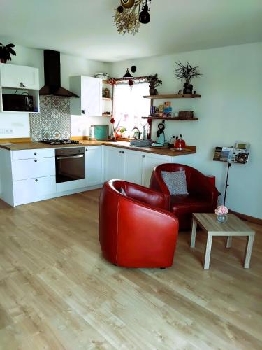une cuisine avec une chaise en cuir rouge et une table dans l'établissement Cottage Lillstugan proche de la Baie de Somme, à Quesnoy-le-Montant
