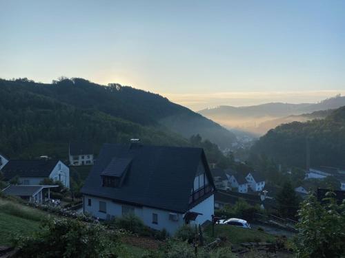 a house on a hill with mountains in the background at Ganze Ferienwohnung in idyllischer Umgebung in Werdohl