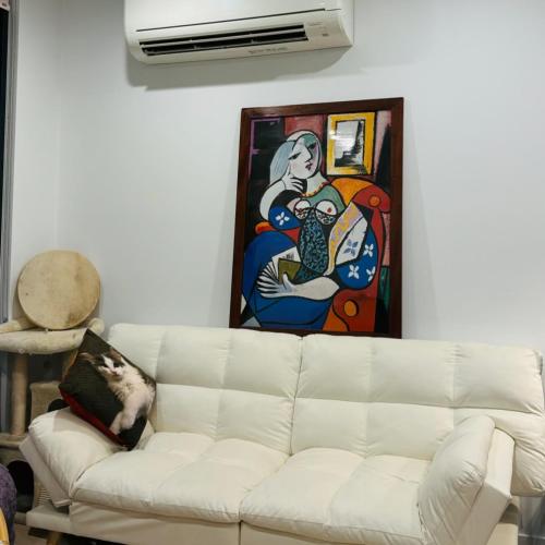 a white couch in a living room with a painting at Cozy 1 Bedroom Apt Parkside Pool Gym Parking close CBD in Melbourne