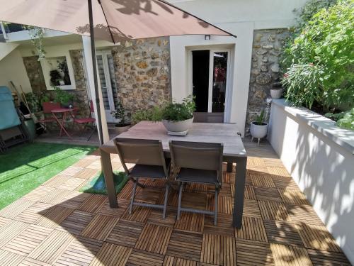 - une table en bois avec des chaises et un parasol sur la terrasse dans l'établissement Agréable logis au calme avec jardin entre PARIS et EURODISNEY, à Rosny-sous-Bois