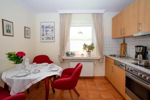 una cocina con una mesa con sillas rojas y una ventana en Sylter Seestern App Momme, en Morsum