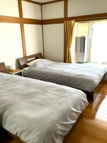a bedroom with two beds and a window at 秋田ゲストハウス　BASE464 in Akita