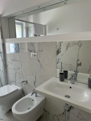 a white bathroom with a sink and a mirror at Aqua Marine B&B - Rooms and Apartments in Milazzo