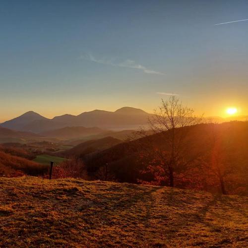 a sunset on a hill with mountains in the background at BnB Bagno di Bosco in Gubbio