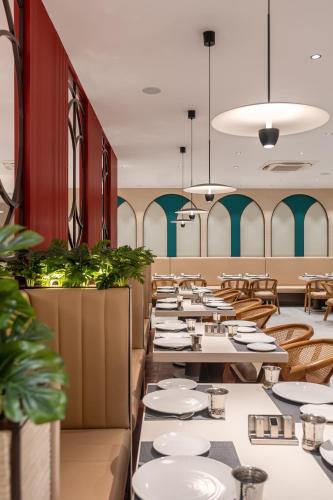 a dining room with white plates on tables at Copper Leaf Hotels, Tirunelveli in Tirunelveli