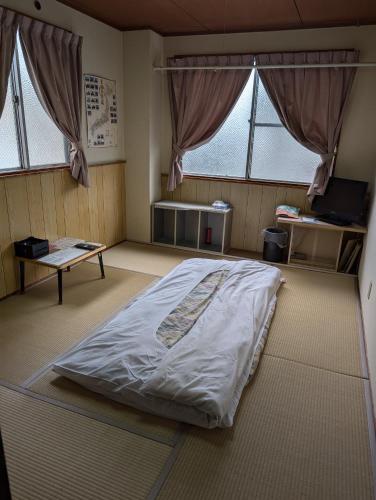 a large bed in a room with two windows at ビジネスホテルみやこ in Higashi-osaka