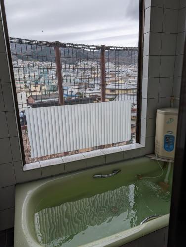 a bath tub in a bathroom with a window at ビジネスホテルみやこ in Higashi-osaka