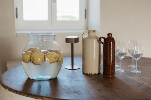 a table with a vase of water and wine glasses at Masseria Vaccaro by Raro Villas - Self Check-in in Brindisi