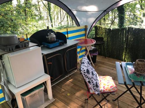 une vue extérieure d'une tente avec un poêle dans l'établissement Camping Au Lac Du Drennec Glamping Tent, à Commana