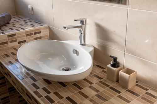 a white sink in a bathroom with a tiled floor at Villa Bona - Private Pool Oasis in Mostar