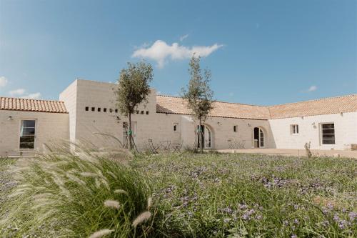 a building with a field of flowers in front of it at Masseria Vaccaro by Raro Villas - Self Check-in in Brindisi