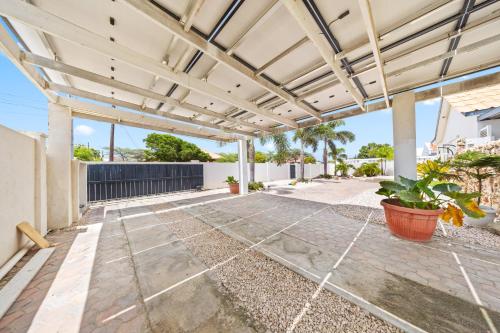 an outdoor patio with a pergola and plants at Ierlandstraat 23 in Oranjestad