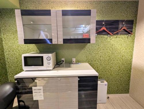 a kitchen with a microwave and a counter top at もしもしピエロ 泉大津新館 in Izumiotsu