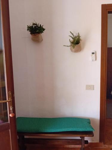 a green bench against a white wall with potted plants at dammuso rosa in Pantelleria